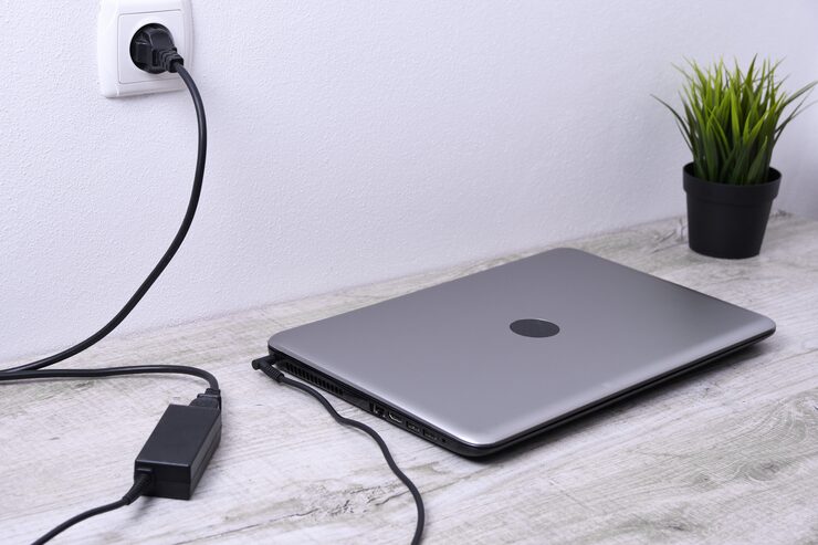 laptop computer is charging from 220 volt outlet desk near wall energy accumulation 150455 1772